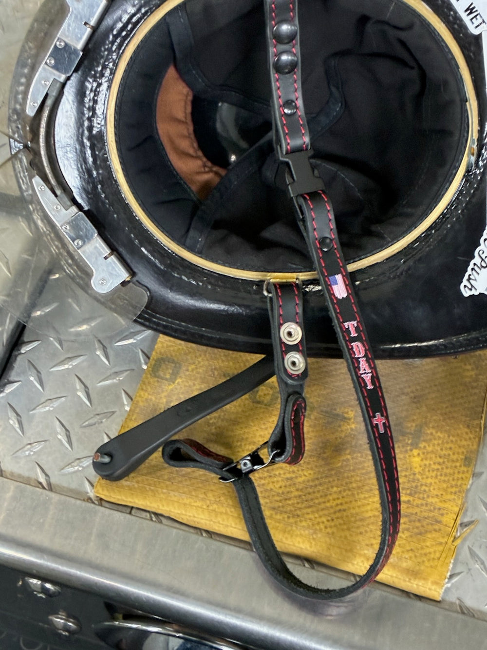 Black leather Box 31 chin strap in service with a customer in New York State, customized with hi-def direct-to-leather printing. A distressed American flag appears at the top, T DAY is printed below in red letters with a white outline, and a cross appears beneath the name.
