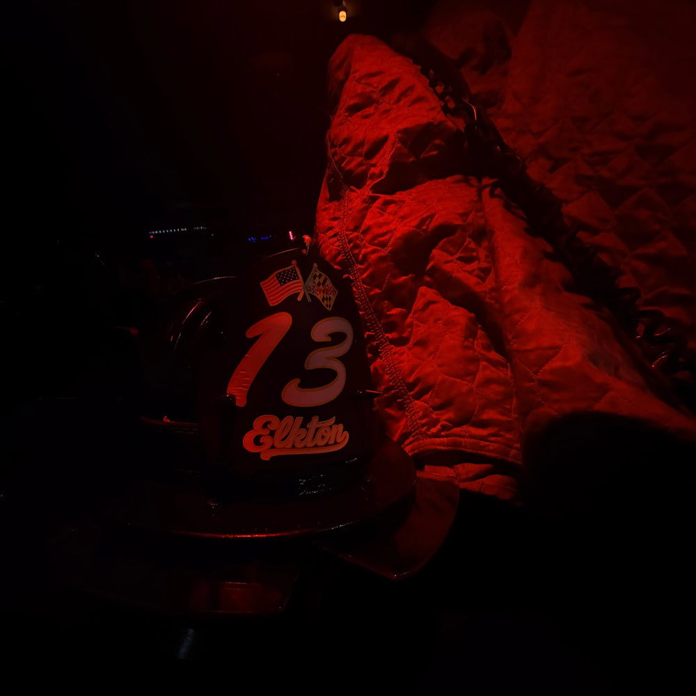 A fully custom Box 31 Boston-style shield has a large number 13 w/ "Elkton" below it in a script font. The shield is installed on a helmet which is gently lit in red scene lights.