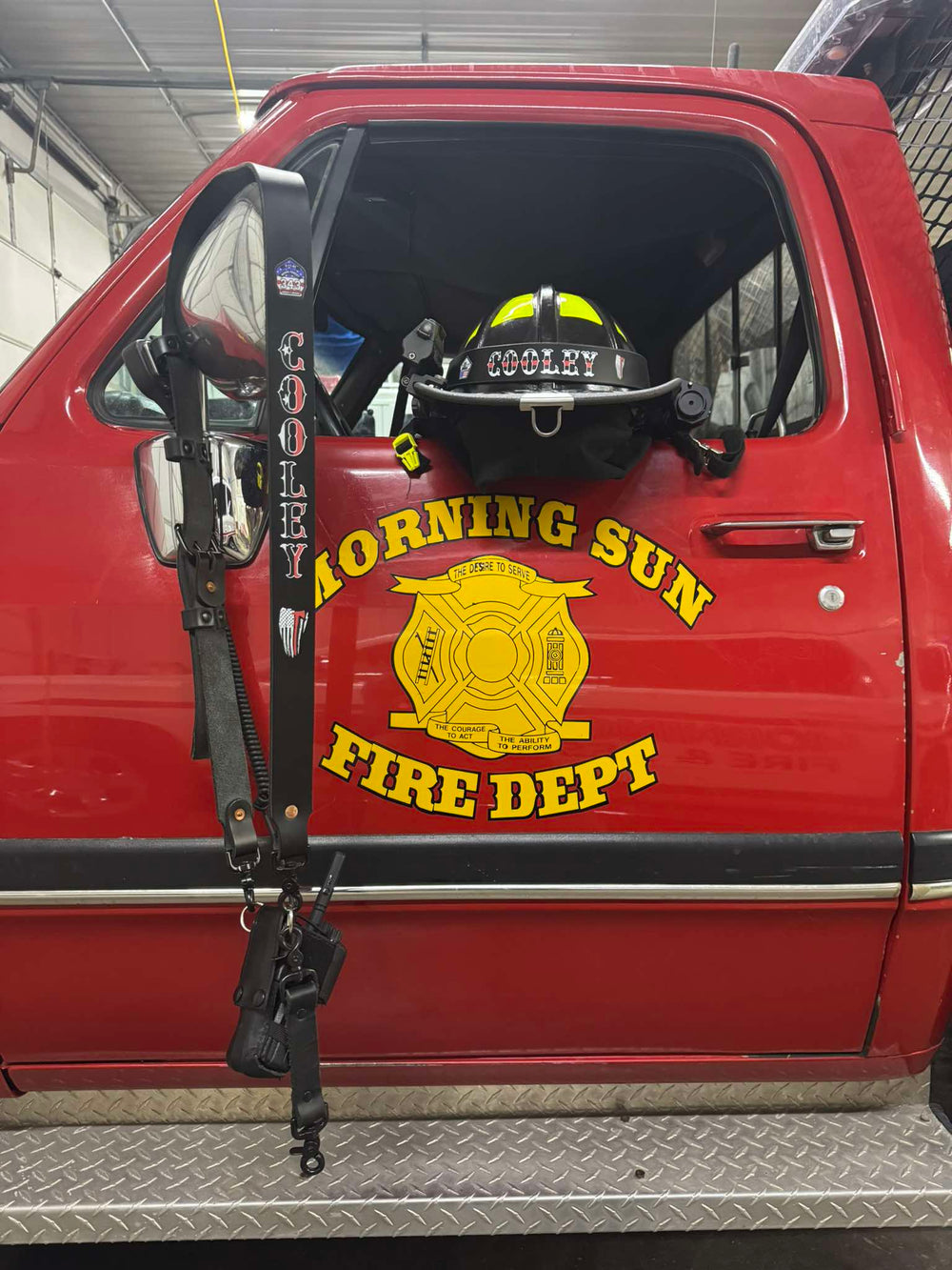This Box 31 hi-def radio strap and helmet band are black leather with red, white and black Thin Red Line text fill, in service and ready to rock on the door of a Morning Sun, Iowa, FD truck.