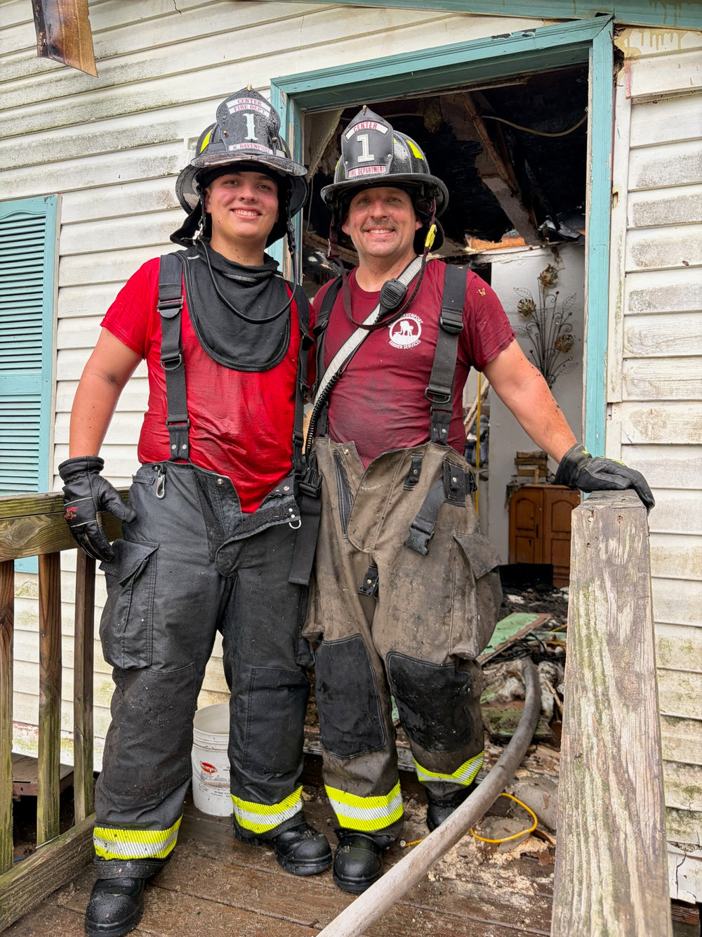 Two firefighters stand on a porch... the one on the left has a Box 31 shield on his helmet. Both men are smiling. New shield, first interior fire, got to fight fire with his dad.