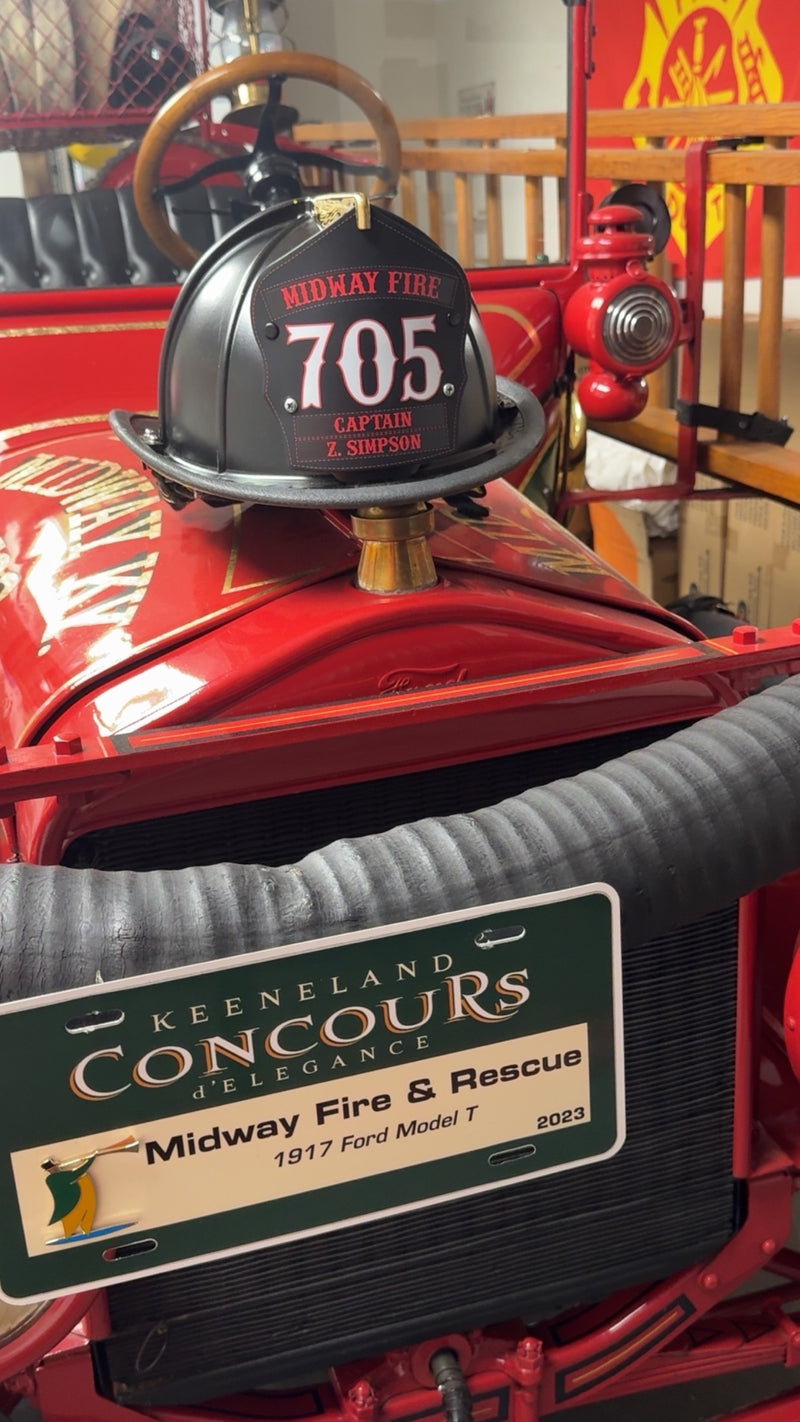 A black helmet with a black and red Box 31 traditional-style shield is perched on the hood of a meticulously maintained 1917 Model T engine, which was the first non-horse-drawn engine of the Midway (KY) Fire Department.