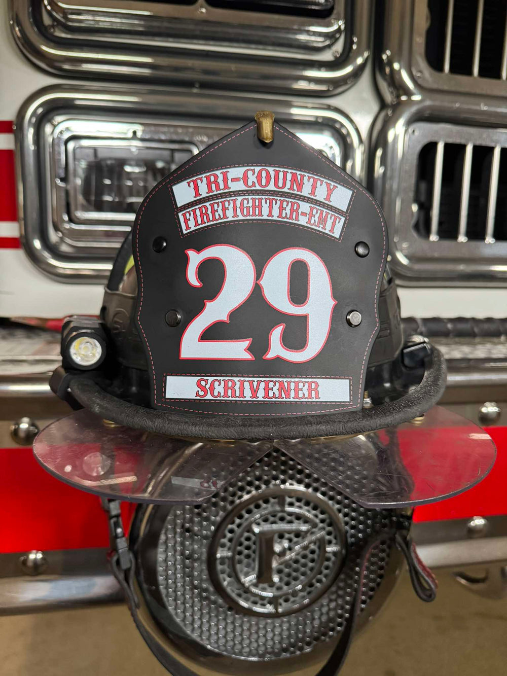 This traditional-style Box 31 helmet shield has white lettering with red outlines printed direct to black leather, in service in New Jersey.